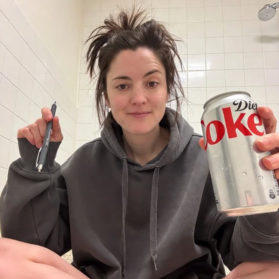 Tired selfie with messy hair holding Zepbound pen and Diet Coke.
