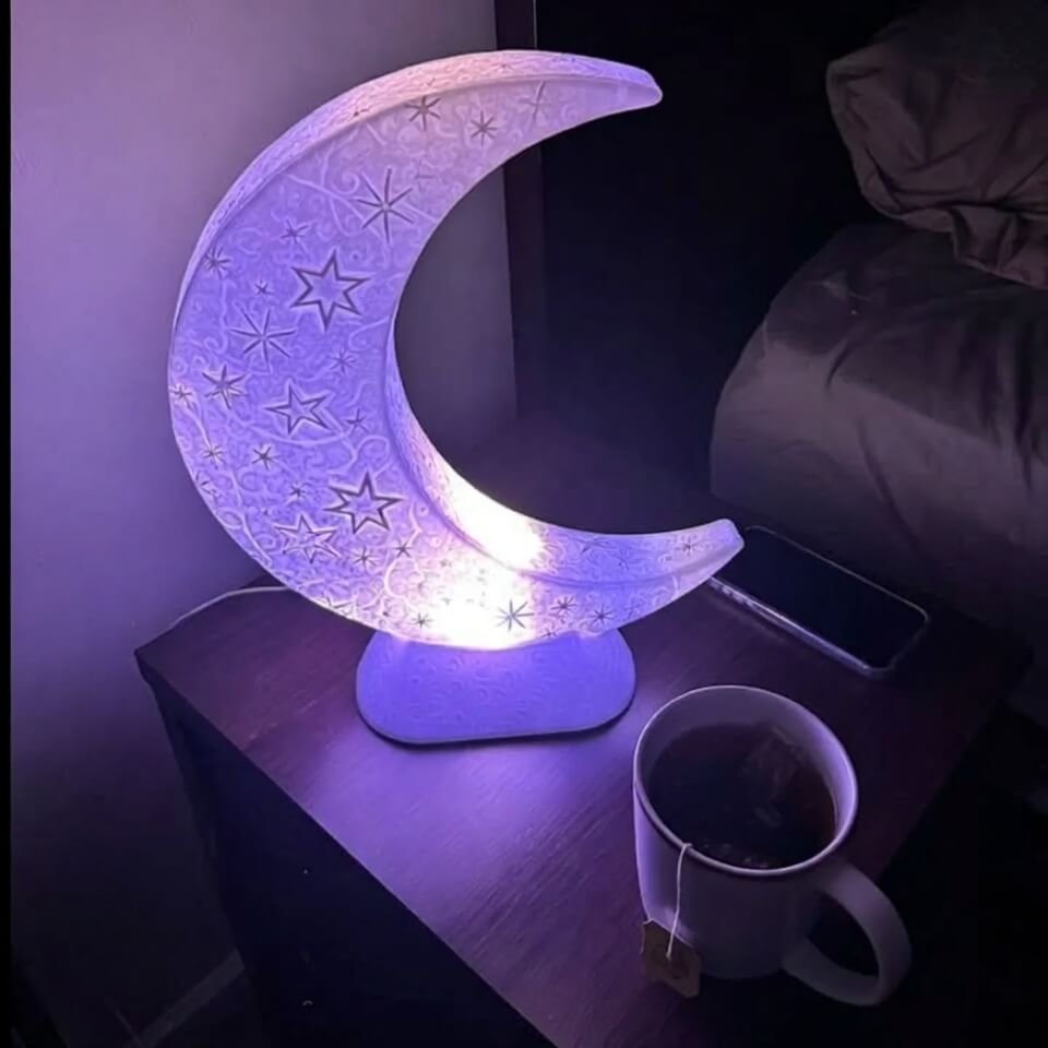 Guilty nightstand snapshot: moon lamp, cold tea, lit phone screen.
