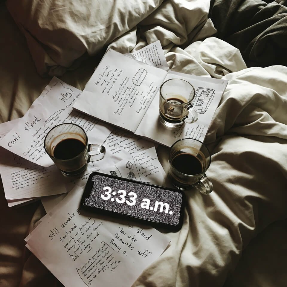 Messy bed with scattered sleep diary pages and 3:33 a.m. phone